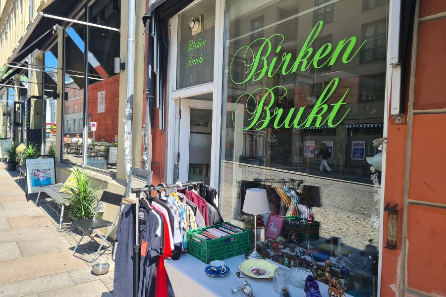 Utenfor inngangen til Birken Brukt på Grunerløkka med klesstativ og et bord med ting og tang
