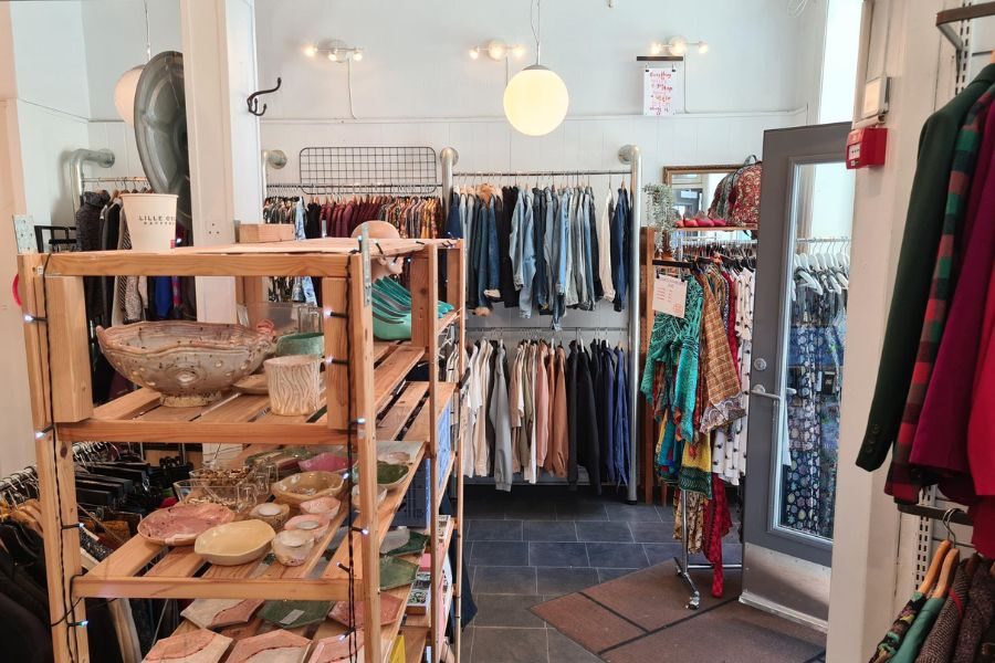 Inngansdøren hos Lykka på Løkka med klær på stativ og tilbehør i hyller