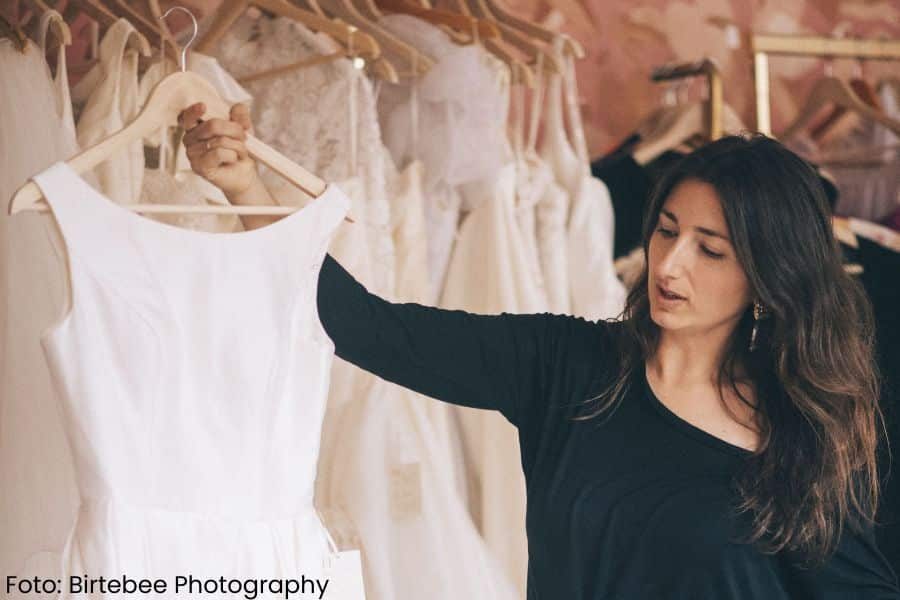 Daglig leder ved Helena Vintage holder opp en brudekjole