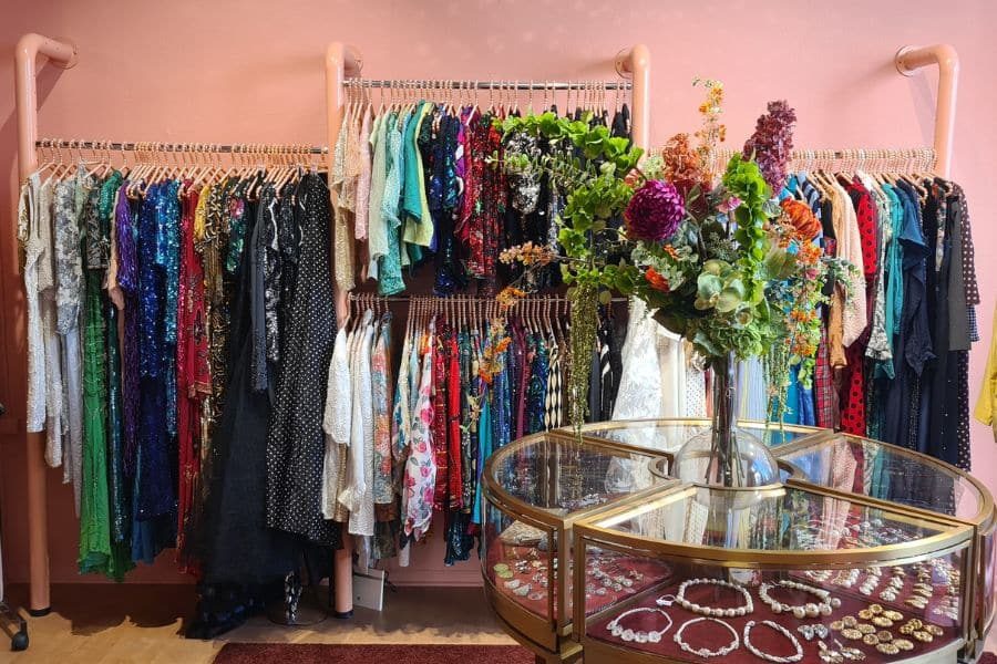 Smykkebord med blomster og kjoler på stativ hos Blusesalongen på Grunerløkka