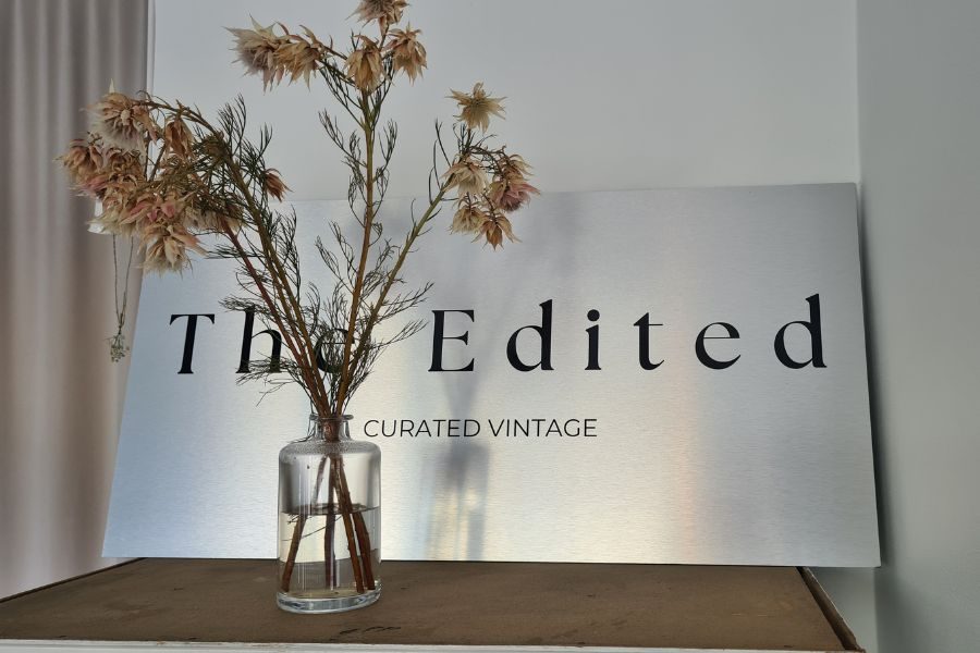 Metallskilt med The Edited gravert inn med tørkede blomster i en liten vase foran hos The Edited på Bislett