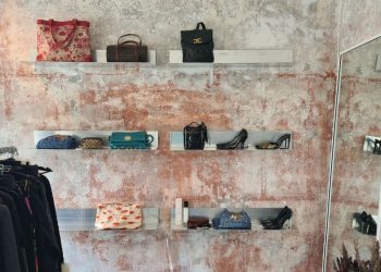 Murvegg med hyller med secondhand og vintage sko og vesker hos The Edited
