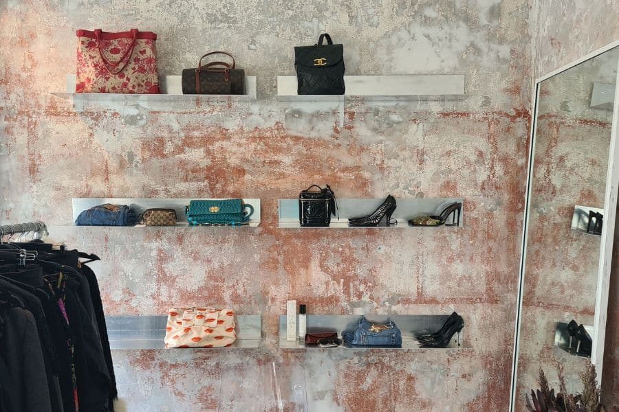 Murvegg med hyller med secondhand og vintage sko og vesker hos The Edited