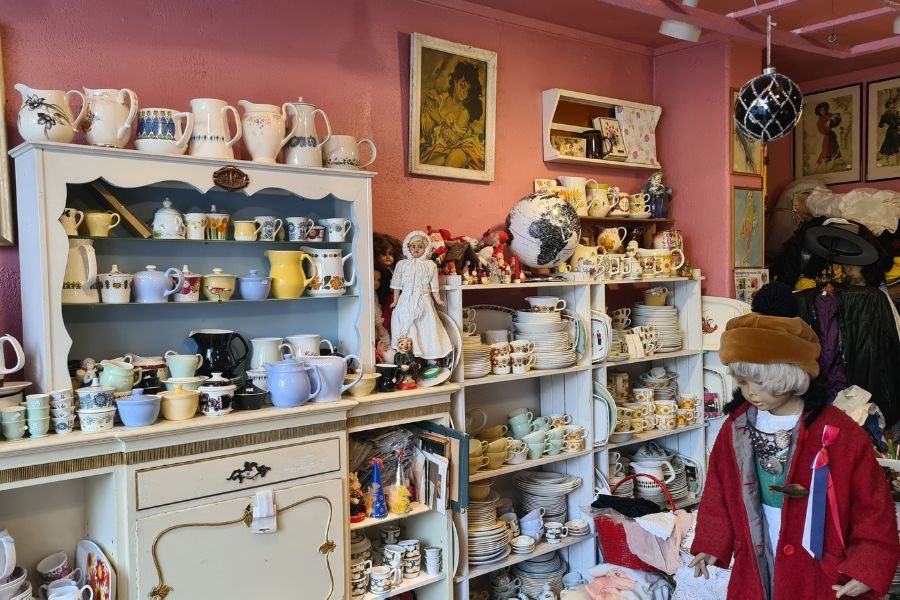 Gamle hyller og skap med service og kunst på vegg hos Dukkehjem på Grunerløkka