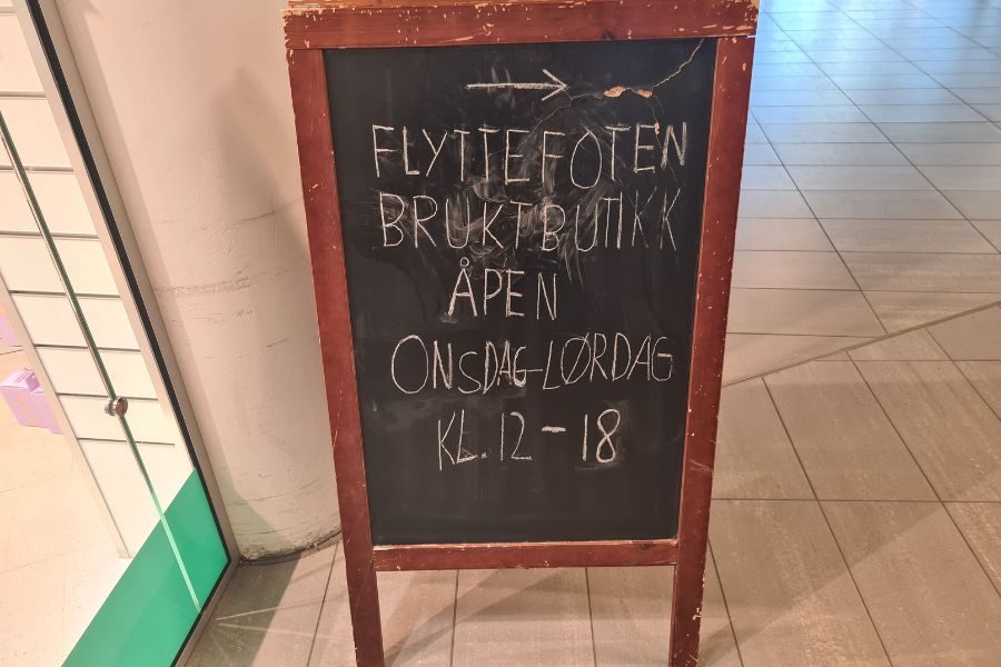 Skilt med åpningstider for Flyttofoten bruktbutikk