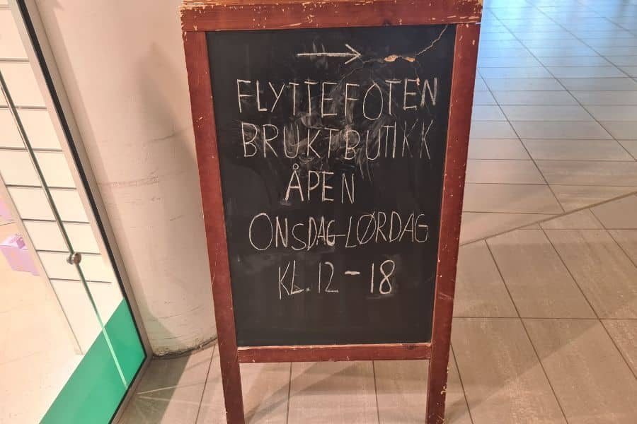 Skilt med åpningstider for Flyttofoten bruktbutikk