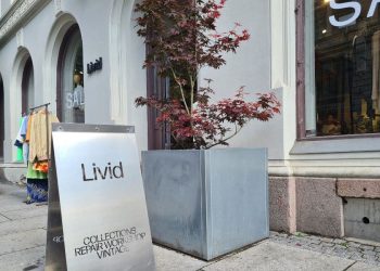 Skilt utenfor hovedinngangen til Livid Oslo, et tre og stativ med vintageklær utenfor