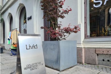 Skilt utenfor hovedinngangen til Livid Oslo, et tre og stativ med vintageklær utenfor