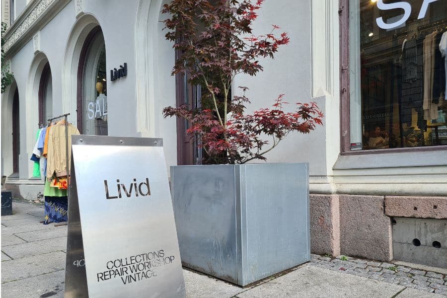 Skilt utenfor hovedinngangen til Livid Oslo, et tre og stativ med vintageklær utenfor
