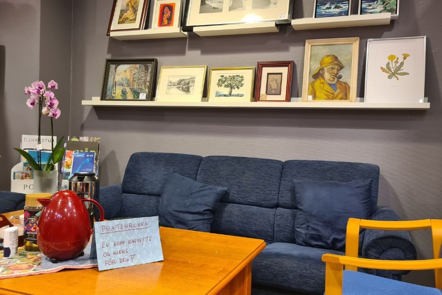 Sofagruppe, kunst på vegg og kaffe på bordet hos Galleri Normisjon Bekkestua