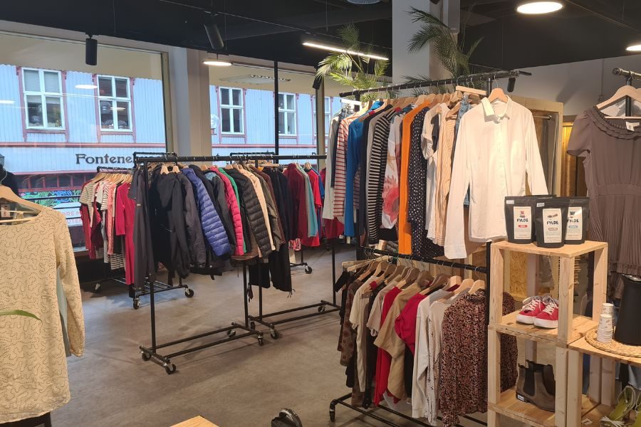 Stativer med klær i lyse lokaler hos Thrift Tøyen