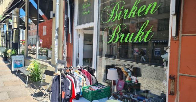 Utenfor inngangen til Birken Brukt på Grunerløkka med klesstativ og et bord med ting og tang