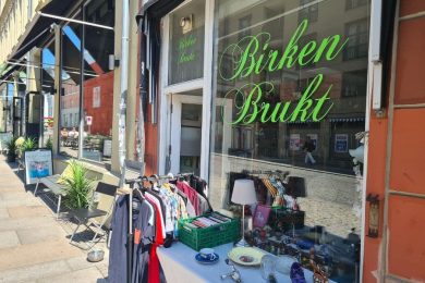 Utenfor inngangen til Birken Brukt på Grunerløkka med klesstativ og et bord med ting og tang