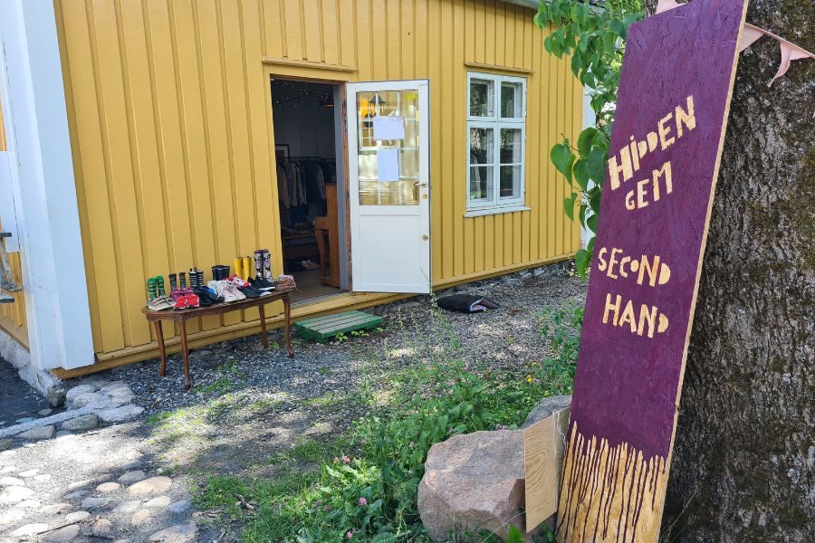 Utenfor inngangen til Hidden Gem med stort skilt lent inntil et et tre